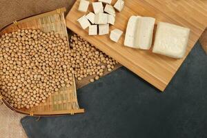 Soyabeans curd tofu soya beans flowing bamboo sieve wooden board on jute black stone slate background photo