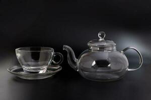 Empty transparent glass see through teapot kettle coffee tea cup saucer set on black background photo