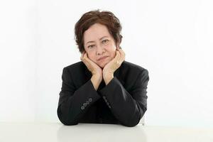 Elderly asian Chinese female on white background wearing black suit thinking hand on cheek look down photo