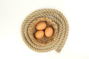 Egg in straw basket jute rope circle around on white background photo