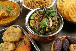 Bengali Iftar Ramadan breakfast spread ripe dates peep fried spicy piaju onion fitter eggplant tanpura potato chop haleem jilapi khichuri rice chana sola curry on rustic wooden table photo