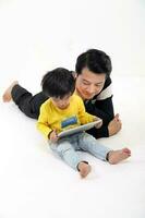 South East Asian father son child playing talking with tablet pc tab on white background photo