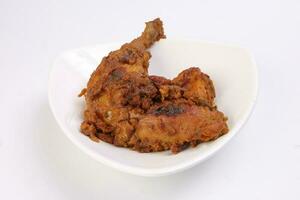 Indian style chicken curry pot roasted leg on white triangle dish over white background photo