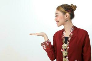Asian woman traditional red maroon kebaya sharong on white background showing display look palm of hand photo