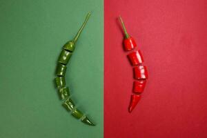 green red chilli pepper on green red paper background cut pieces seeds photo