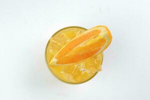 Fresh yellow orange juice in glass with orange slice and ice cube on white background photo