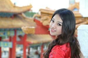 Young south east asian Chinese man woman traditional costume Chinese new year greeting outdoors at temple photo