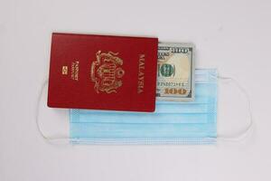 US Dollar currency paper money 100 Hundred dollar bill red malaysian passport book face mask on white background photo