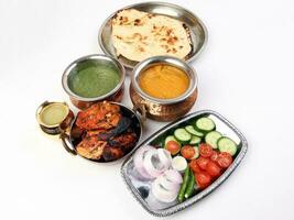 Spicy red Chicken grilled tikka tandoori nan bread green spinach curry yogurt sauce dal tomato cucumber onion salad set in metal stainless steel brass copper pot on white background photo