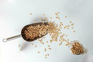 Depth of filed soya been pouring splashing from hart shape glass bottle over metal scoop photo