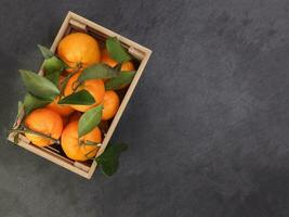 mandarin orange green leaf in wooden box crate top view copy text space on black slate marble background photo