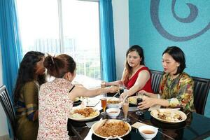 Young southeast asian woman group talk celebrate eating enjoying food rice curry noodle chicken drink cheers on dining table photo