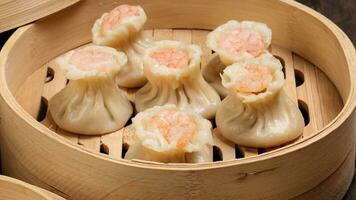 Prawn shrimp shaomai dim sum dumpling in bamboo steamer on rustic wood background photo