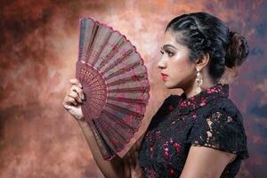 South east Asian Indian race ethnic origin woman wearing Chinese dress costume Cheongsam holding hand fan multiracial community on retro vintage background photo