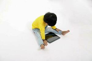 South East Asian young boy child playing tablet tab computer pc on white background photo