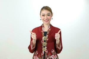 Young attractive Asian woman traditional red maroon nyonya kebaya sharong on white background happy smile confident photo