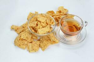 Keropok Tauhu tofu flower sugar chips with blackseed with cup of transparent licker tea photo