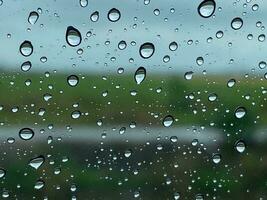 Rain drop on car window glass green paddy field background rainy cloudy day photo