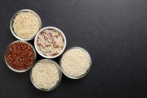 Long grain basmati medium grain jasmine short grain pilaf polau risotto brown low glycaemic index gi rice in small glass bowl on black background copy text space top flat lay view border frame photo