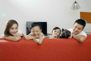 Parent mother father little child boy girl brother sister happy smile looking over the sofa photo