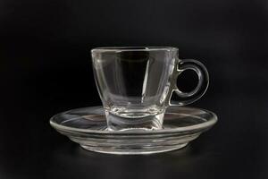 Empty transparent glass see through coffee tea cup saucer on black background photo