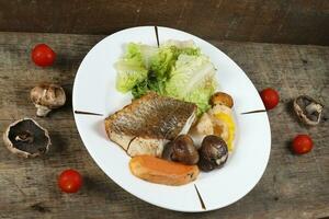 A la parrilla lubina vegetal y ensalada seta tomate foto