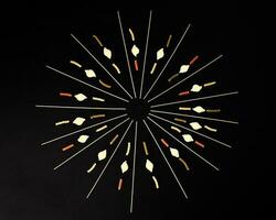 dry raw spaghetti conchiglie seashells fusilli cork screw color pasta laid on black background sunray glow pattern concept photo