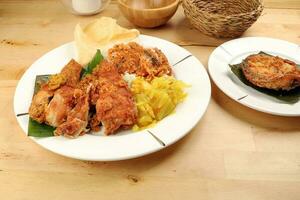 Traditional Malaysian Indian food white rice cabbage vegetable meat deep fried chopped chicken leg topped up with spicy mix gravy wood table background photo