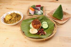 Nasi Lemak fragrant rice coconut milk with sambal friend peanut anchovy egg packed banana leaf round bamboo plate colorful nyonya kuih sweet desert palm leaf plate on wooden background photo