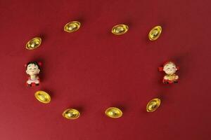 Chinese boy girl doll figurine money syce ingot gold on red background copy space photo