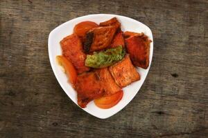 Pan friend salmon fish fillet in white triangular plate on rustic wood background photo
