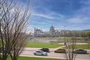 View on Vilnius river buildings and cars from Sakura Park with starting to bloom japanese cherries with high blue sky with clouds photo