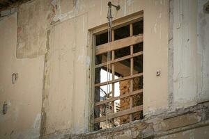 Old window with metal trellis outside abandoned aged house with visible open window on the opposite wall of the room photo