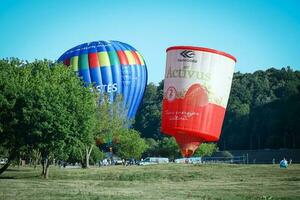 kaunas, Lituania 20 10 2022 dos azul y rojo aire globos en pie alto en césped Entre verde arboles antes de volador arriba a el azul cielo en soleado día foto