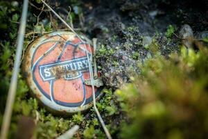 Vilnius, Lithuania - March 30 2023 Old rusty bottle cap on a forest floor with green moss photo