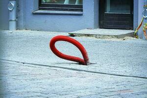 Cable in red corrugated tube sticking out of paved road on a city street photo