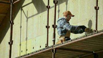 minéral la laine blocs sur maison mur. extérieur des murs isolant processus. construction ouvrier. video