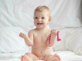 Baby on Bed Playing With Beads photo