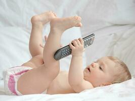 Baby lying and playing with remote control photo