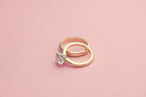 Engagement and Wedding Rings on Pink Background photo