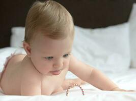 Blond baby girl lying on bed photo