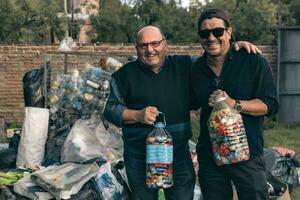 Two men at a recycling center, happily and proudly showing off the work they have done. photo