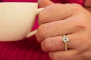 Diamond Ring in Hand on a Pink Knitted Sweater photo