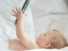 Baby lying and playing with remote control photo