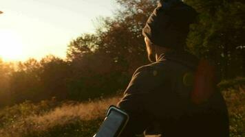 Outdoormann mit Kopfhörer genießen szenisch Sonnenuntergang im ein Wald. schleppend Bewegung Filmaufnahme. video