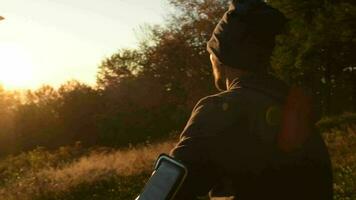 homme de plein air avec écouteurs profiter scénique le coucher du soleil dans une forêt. lent mouvement images. video