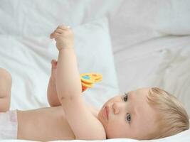 Baby lying and playing with toy photo