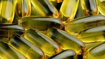 transparent yellow pills with liquid inside slowly turning, full-frame close-up video