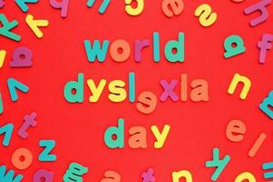 Color alphabet letters on red background. World Dyslexia Day concept. Solving the educational problem of reading. Medical and mental health awareness. Logopedy, psychology, learning lessons photo