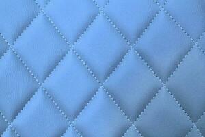 Close-up texture of blue stitched threads leather with seam background. Rhombus pattern for interior car, sofa, wall covering, headboard. Natural material on furniture backdrop. Classic design photo